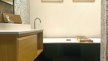 A bathroom with a wooden vanity, a freestanding sink, and two framed pictures on the wall.