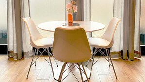 A dining area with a round table and four chairs, a vase with flowers, and a view through large windows with curtains. - Luxe studio with vintage look in  ‘a New Village on New Land’ Nagele (Nagele)