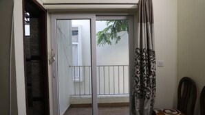 Et værelse med en skydedør, der fører ud til en balkon med gelænder. Der er en mønstret gardin på dørens højre side.