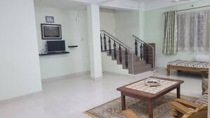 Un amplio salón con una escalera, un televisor de pantalla plana, una mesa de centro y un sofá.
