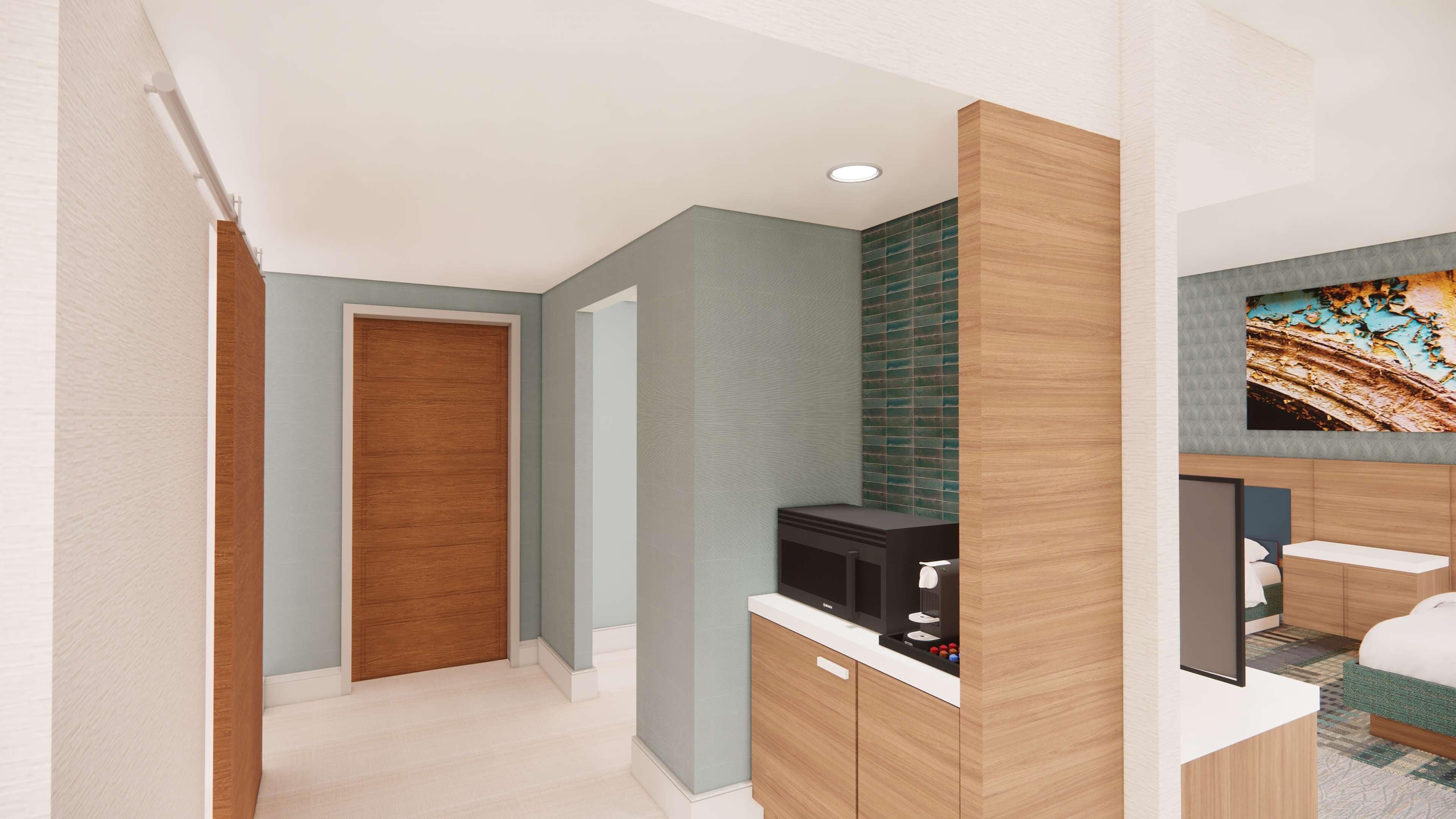 A modern hotel room with a wooden door, a minibar, and a television on the wall.