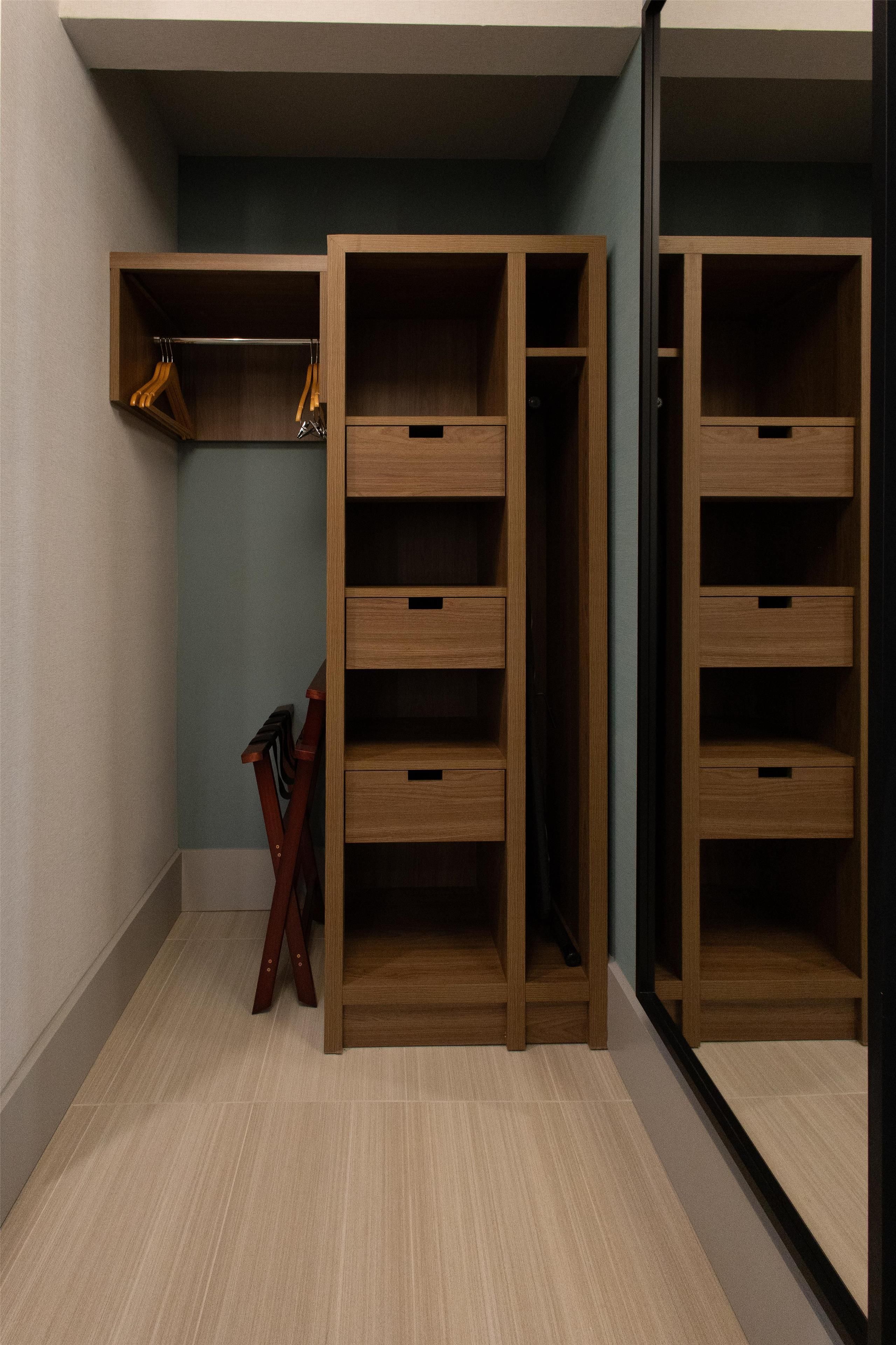 Un armario con varios estantes y cajones, muebles de madera y un espejo.
