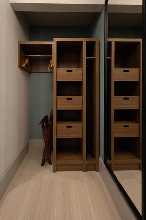 A closet with multiple shelves and drawers, wooden furniture, and a mirror.