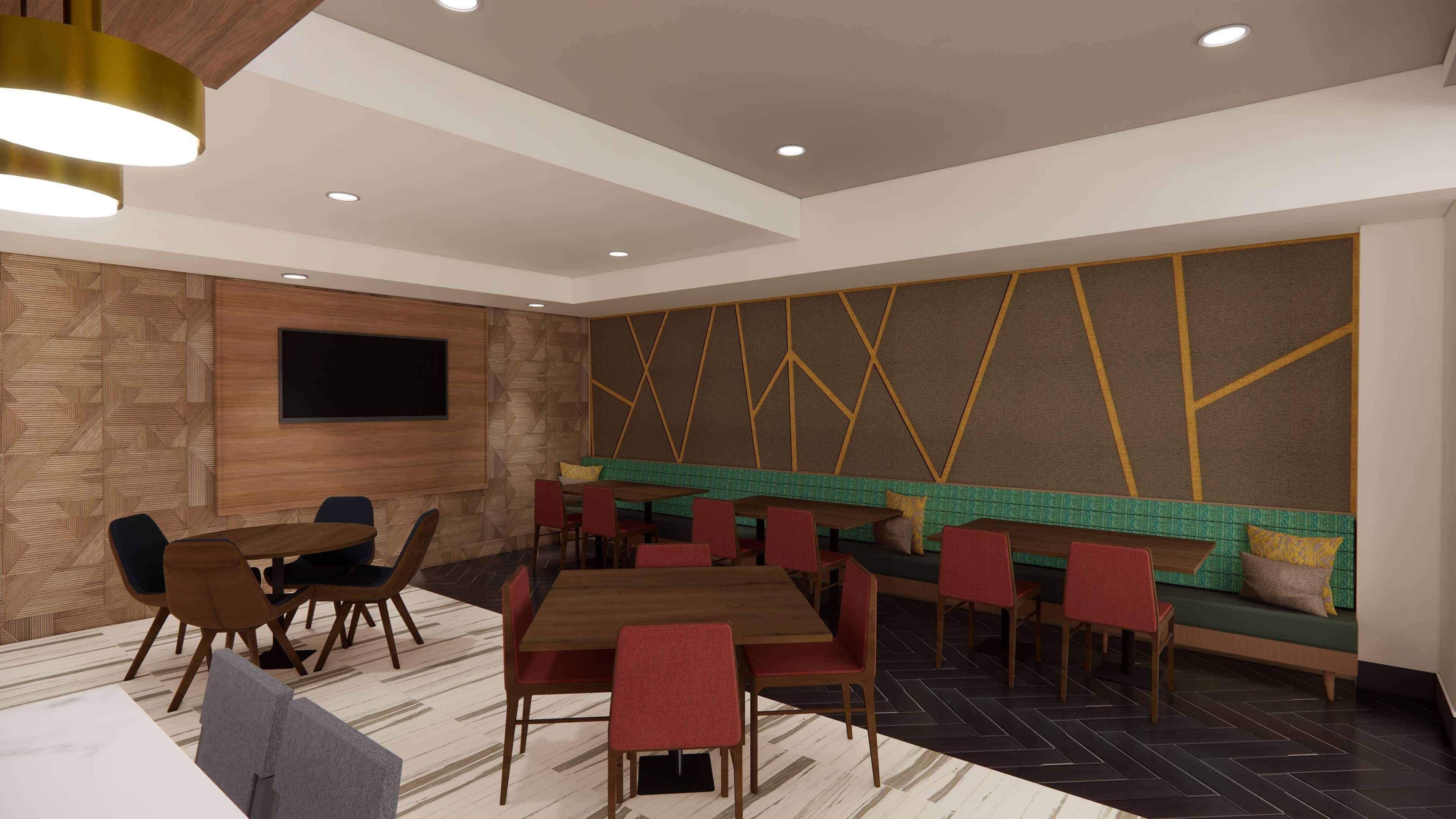 A modern conference room with a large table, multiple chairs, a sofa, and a television mounted on the wall.