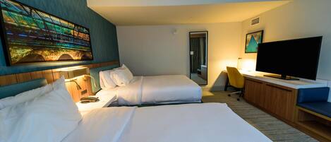 Habitación de hotel con una cama grande, televisión, escritorio y un cuadro en la pared.
