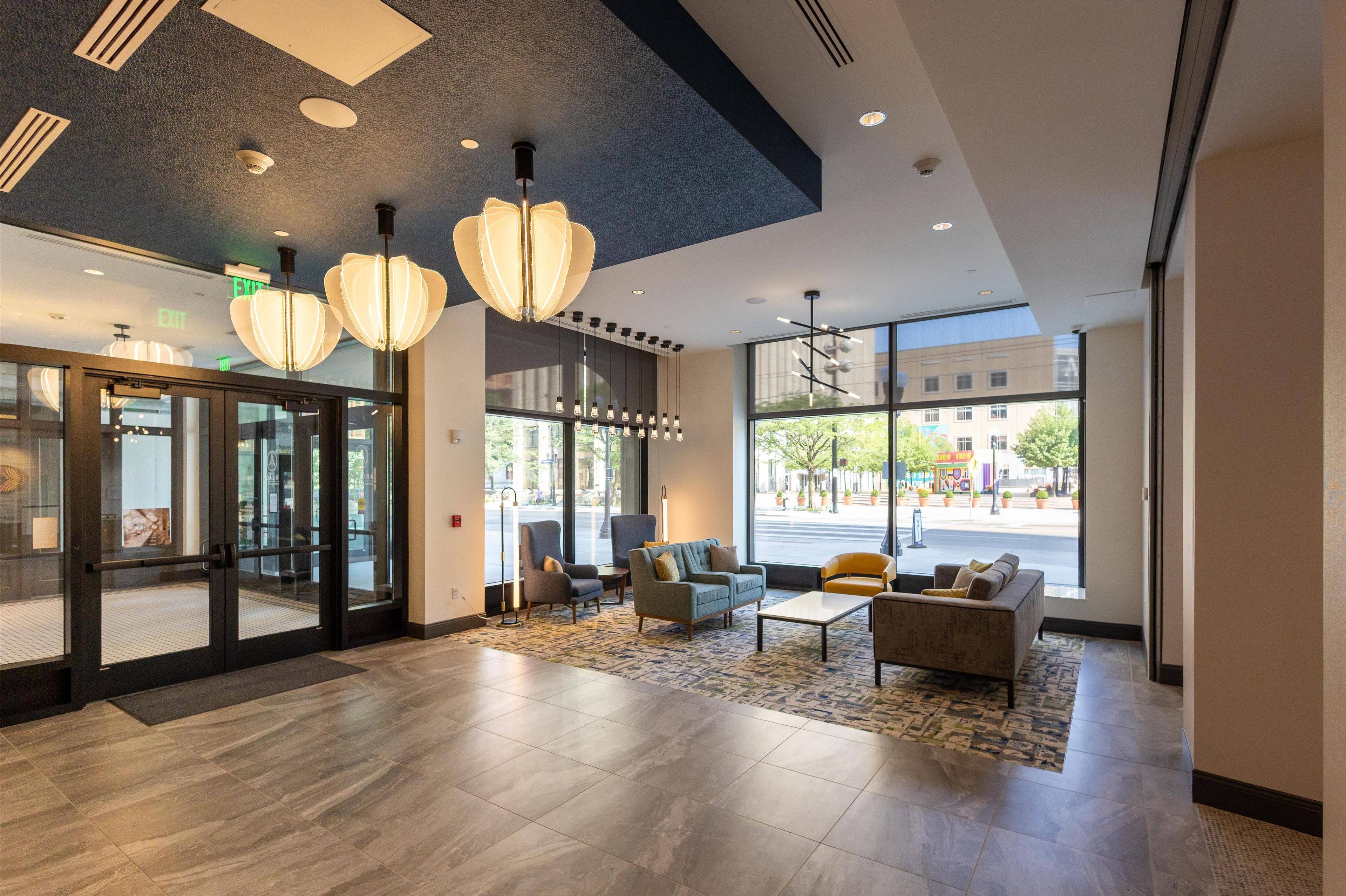 A lobby with modern furnishings, large windows, and a view of the street.