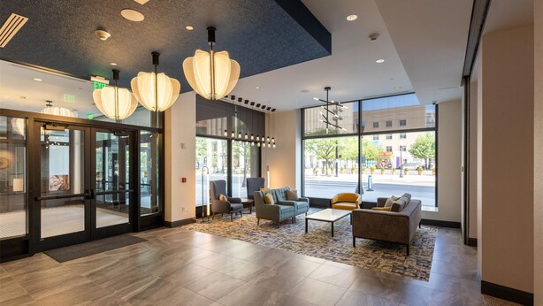 A lobby with modern furnishings, large windows, and a view of the street. - Hilton Garden Inn Dayton Downtown (Dayton)