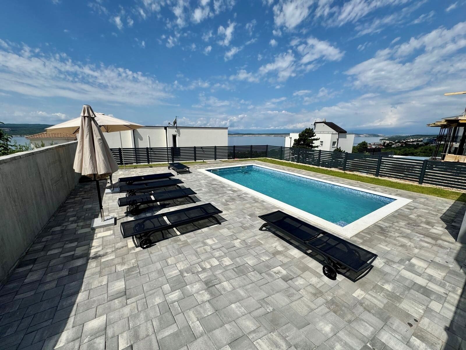 A rooftop pool with lounge chairs and a view of the sea.