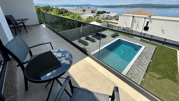 A balcony with a pool, outdoor furniture, and a view of the sea and buildings. - Villa Heavenly Beauty (Crikvenica)