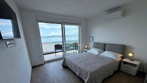 A bedroom with a bed, bedside tables, a TV, and a balcony with a view. - Villa Heavenly Beauty (Crikvenica)