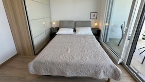 A modern bedroom with a large bed, two bedside tables with lamps, a sliding glass door to a balcony, and a built-in wardrobe. - Villa Heavenly Beauty (Crikvenica)