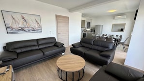 A modern living room with two black leather sofas, a wooden coffee table, and a painting of sailboats on the wall. - Villa Heavenly Beauty (Crikvenica)