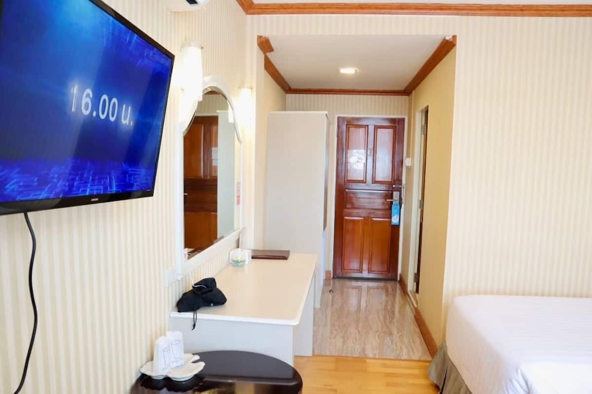 A hotel room with a bed, a desk with a chair, a television, and a mirror.