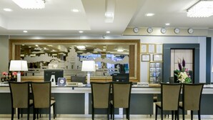 Uma área de recepção de hotel com balcão, cadeiras, caixa registradora e computador.