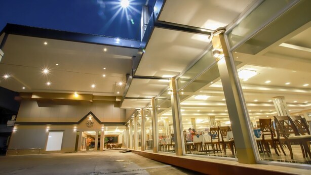 Um edifício moderno com fachada de vidro, vários níveis e interior bem iluminado com mesas e cadeiras.