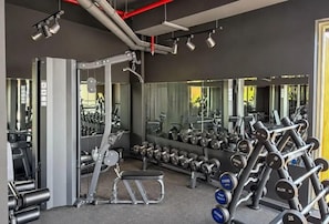 Une salle de sport équipée de divers appareils d’exercice, de miroirs et d’un banc.
