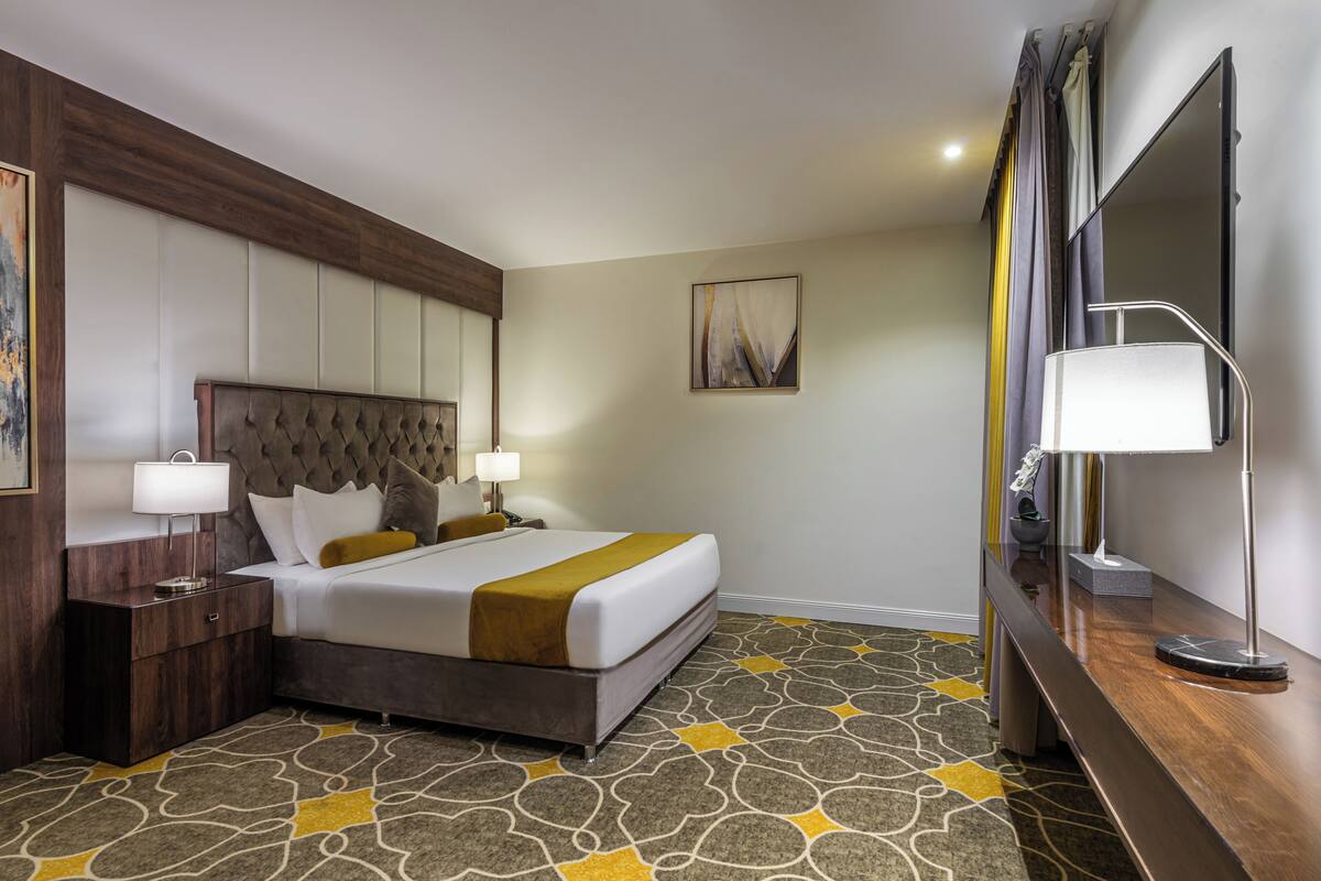 Une chambre d’hôtel avec un grand lit, une table de chevet, un bureau et un miroir.