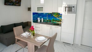 A modern kitchen with white cabinets, a microwave, and a blue-tiled backsplash. - Apartments Sun Dance 2 With Heated Pool (Novalja)