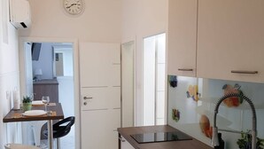 A modern kitchen with a built-in oven, a sink, and a dining area with a chair and table. - Apartments Sun Dance With Heated Pool (Novalja)