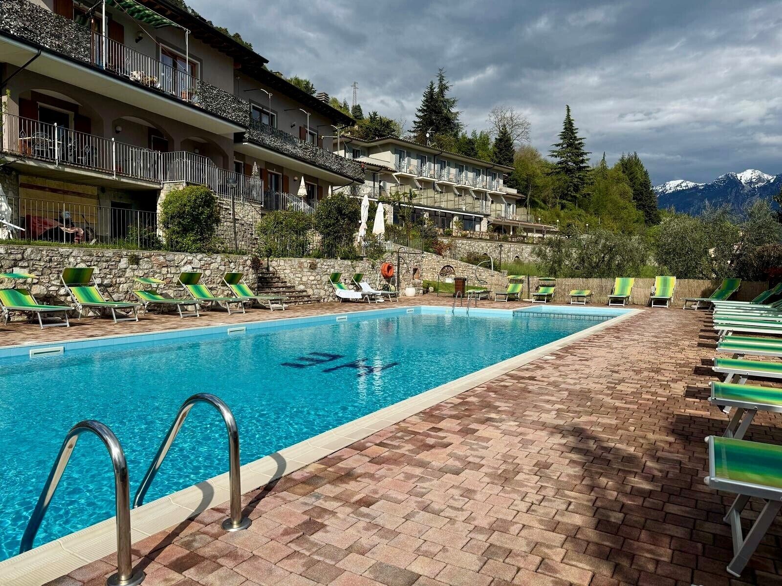A swimming pool with sun loungers and a stone wall.