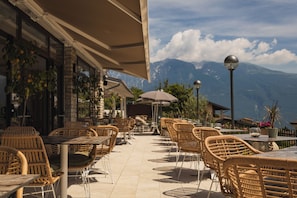 An outdoor cafe with wicker furniture and a view of mountains.