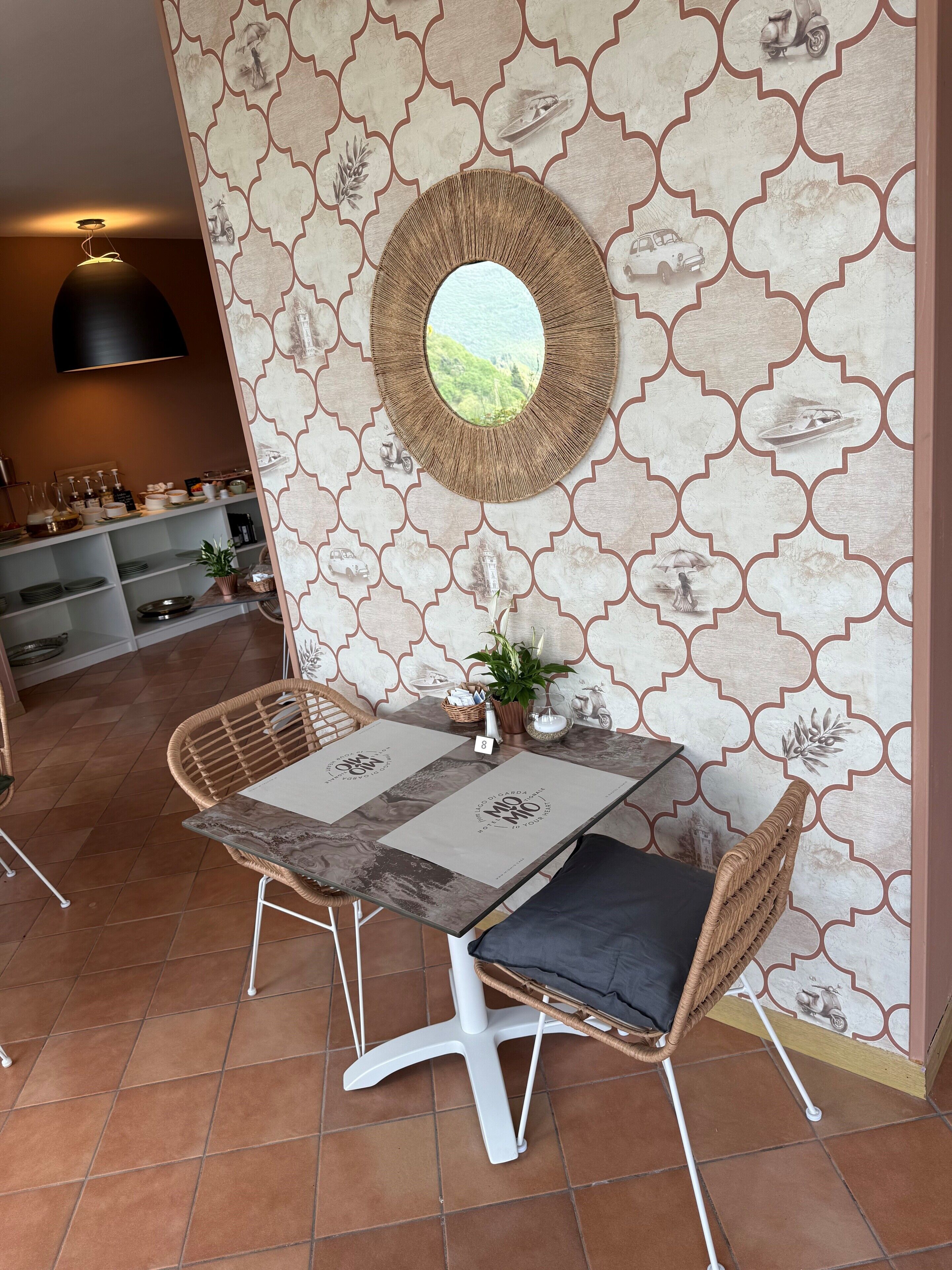 Un coin repas comprenant une table, des chaises et un miroir décoratif accroché au mur.
