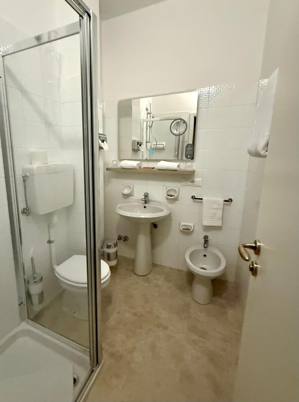A bathroom with a glass-enclosed shower, a pedestal sink, a toilet, and a bidet.