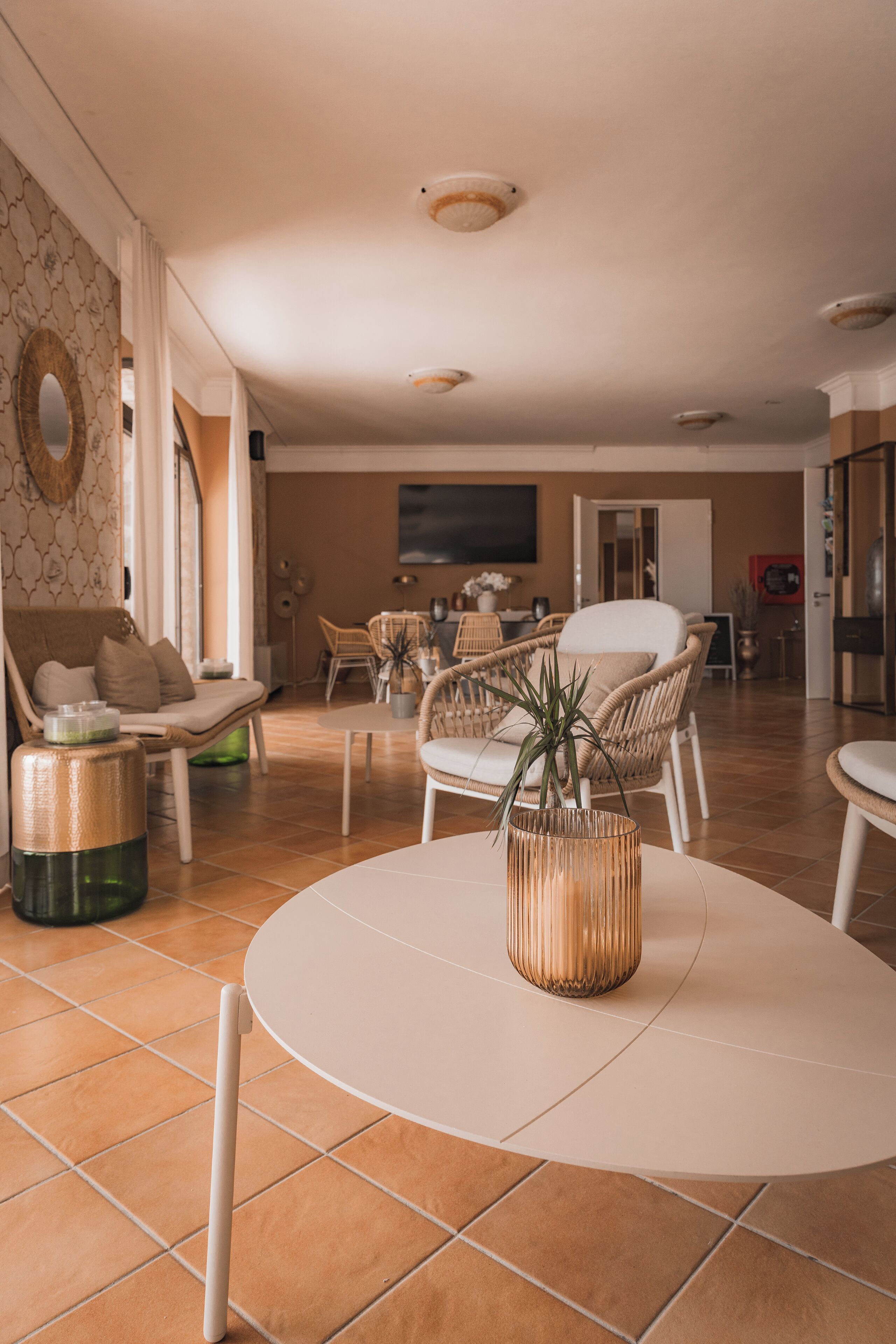 A spacious living room with a round table, wicker chairs, and a sofa.