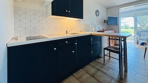 Uma cozinha moderna com armários escuros, bancada branca e painel de azulejos.