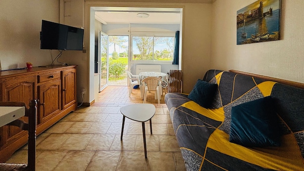 Uma sala de estar com sofá, televisão e área de jantar com mesa e cadeiras.