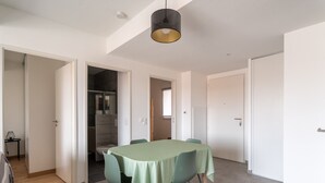 A dining area with a table set for four, surrounded by chairs with wooden legs. There is a ceiling light fixture above the table.