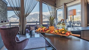 A modern kitchen with a wooden countertop, a fruit platter, and a view of mountains.