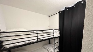 A bunk bed room with white bedding and a black curtain.