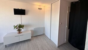 A modern room with a white cabinet, a flat-screen TV, a potted plant, and a sliding door.