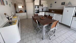 A compact kitchen with white cabinets, a wooden dining table, and a refrigerator. - 3-room apartment, private terrace, sleeps 6 in Port Camargue (Port Camargue)