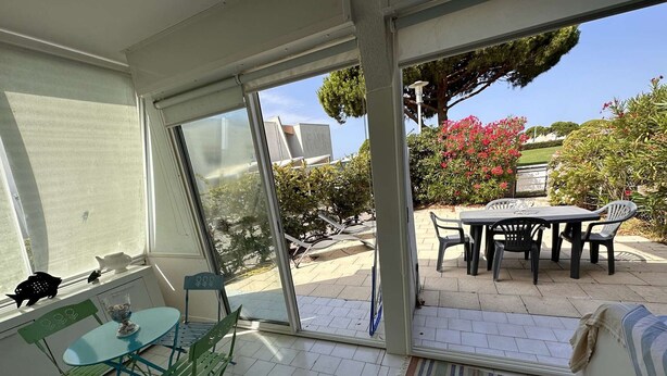 A sunlit patio with a table and chairs, a sliding glass door leading to a garden, and a cushioned seating area. - 3-room apartment, private terrace, sleeps 6 in Port Camargue (Port Camargue)