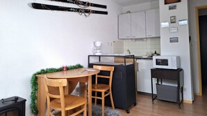 A compact kitchen with a dining area, including a table, chairs, a coffee maker, and a microwave.