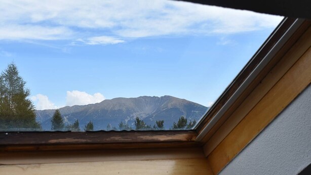 A skylight with a view of mountains and trees.