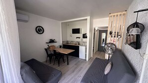 A compact living space with a kitchenette, a dining area, and two grey sofas. - Studio for 4 people in Port Camargue (Port Camargue)