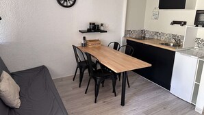 A compact living space with a dining table, chairs, a sofa, and a kitchen area including a microwave and a coffee machine. - Studio for 4 people in Port Camargue (Port Camargue)