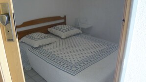 A bedroom with a wooden bed frame, a patterned bedspread, and two pillows.