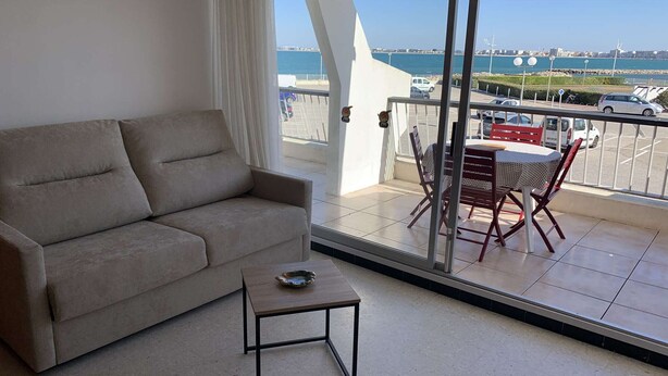 A balcony with a sofa, a small table, and a dining set.