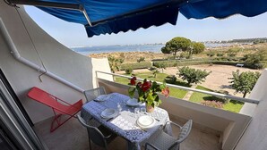 Un balcón con una mesa dispuesta para dos personas, con vistas a un paisaje costero.