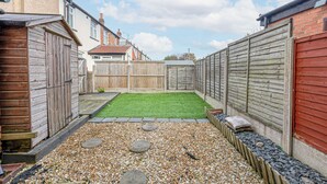 A backyard with a gravel path, a small lawn, and a wooden fence. - Ansdell House, Ansdell Road (Blackpool)