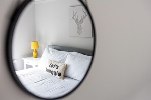 A bedroom with a bed, a nightstand, a lamp, and a wall art piece. - Ansdell House, Ansdell Road (Blackpool)