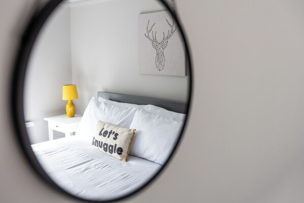 A bedroom with a bed, a nightstand, a lamp, and a wall art piece.
