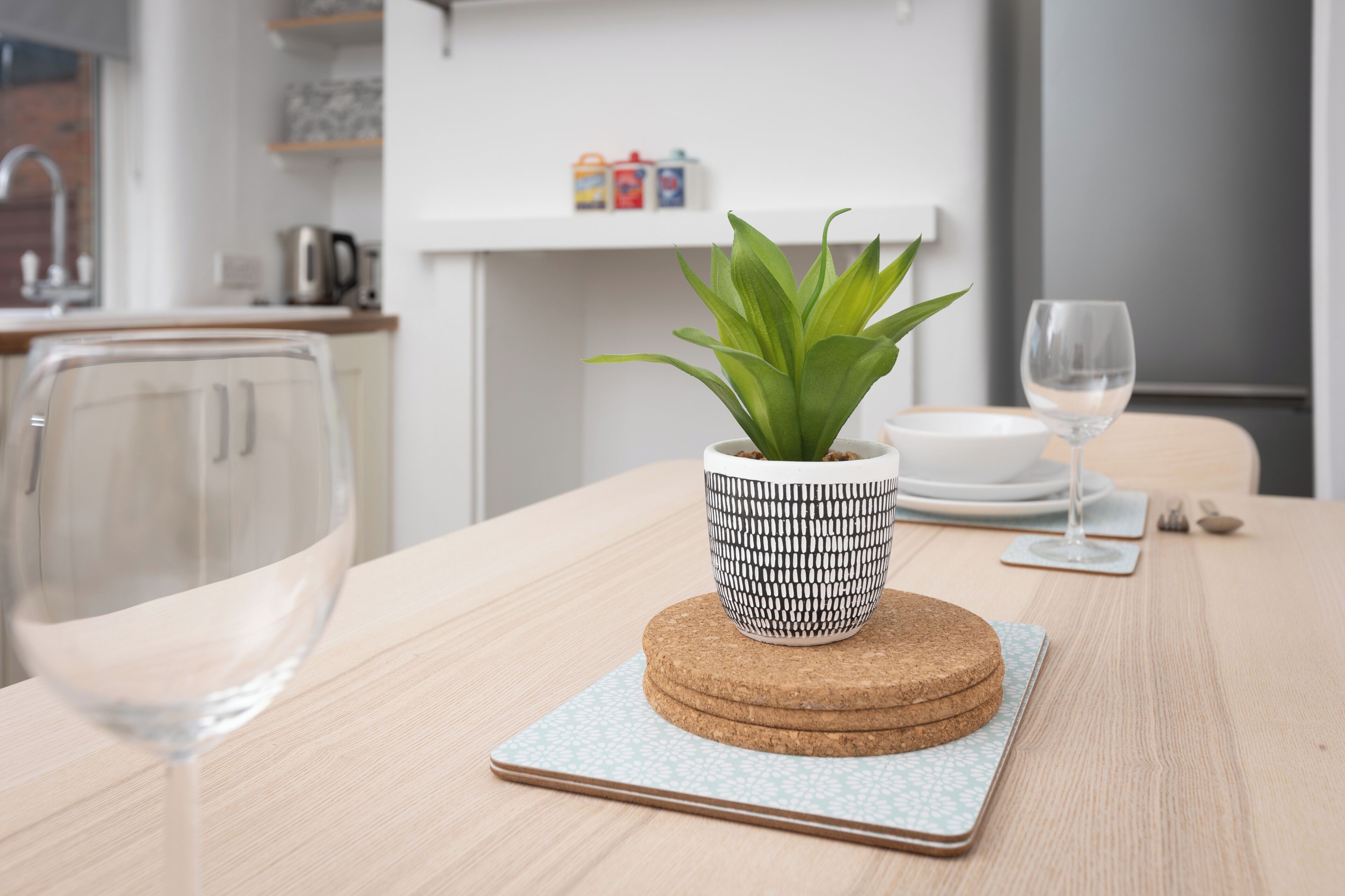 Una mesa con una planta en maceta, un pastel y una copa de vino.