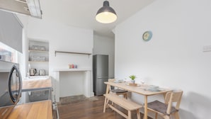 A compact kitchen with a dining area, wooden flooring, a bench, and a clock on the wall. - Ansdell House, Ansdell Road (Blackpool)
