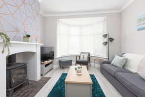 Un salon moderne avec une cheminée, un canapé, une table basse et un téléviseur.