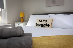 A neatly made bed with a pillow that reads "Let's Snuggle."